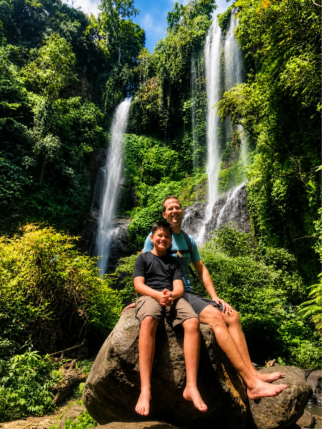 A father and child smiling at a jungle waterfall in North Bali