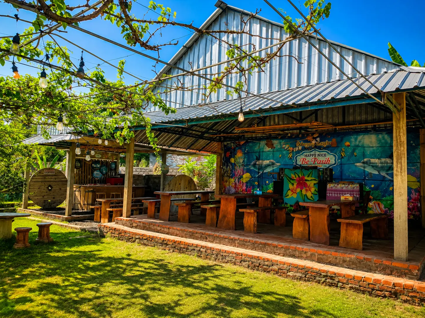 Happy Nice Warung Lesehan food stall with wooden tables and tropical murals